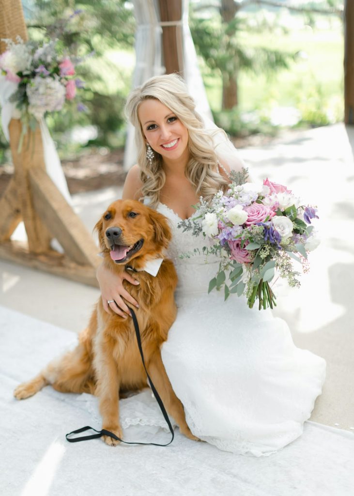 Dog wedding ideas shown in a bride’s portrait with her golden retriever wearing a white bow tie during the ceremony.
