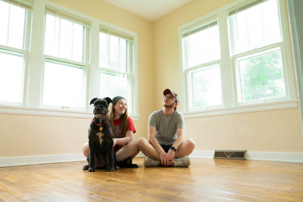 Couple sitting on the floor with their dog during a move, helping their dog through life changes in a new home.